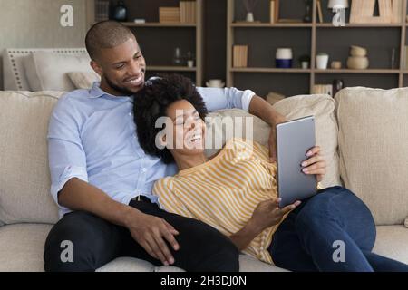 Relaxed smiling millennial mixed race couple using tablet. Stock Photo