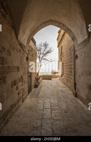 Passageway between stone buildings, old stone arch and in the background a tree and a viewpoint Stock Photo