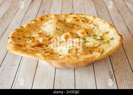 Garlic naan without crumb cooked in a Hindu restaurant on wooden table Stock Photo