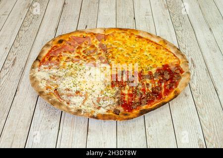 Four seasons pizza with well-differentiated portions with cream cheese with onions, minced meat with barbecue sauce, four melted cheeses and ham with Stock Photo