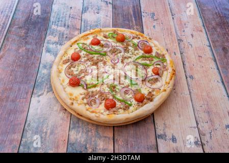 Tuna pizza with cherry tomatoes, red onion and green peppers with oregano and lots of melted mozzarella cheese Stock Photo