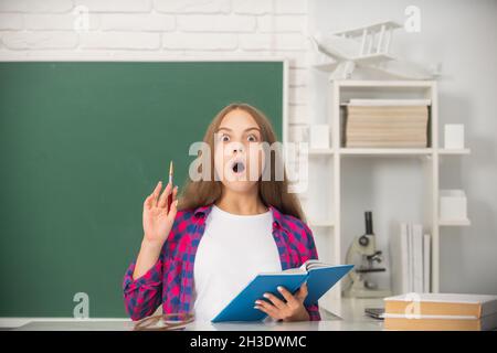 amazed child study at school with book on blackboard background, erudition Stock Photo