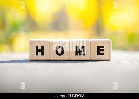 Word HOME made of wooden letter blocks arranged on a tree stump against a blurred autumn forest background. Importance of nature. Stock Photo