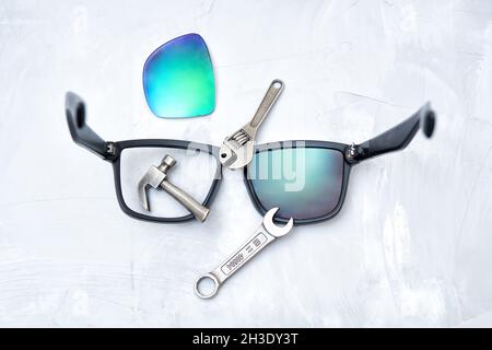 Broken sunglasses with a set of hand tools on a concrete table. Choosing a proper repair tools kit. Stock Photo