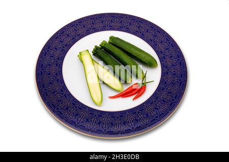 courgette, zucchini (Cucurbita pepo var. giromontiia, Cucurbita pepo subsp. pepo convar. giromontiina), courgettes on a plate, one of them halved Stock Photo