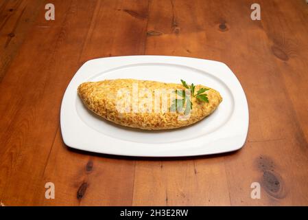Half Spanish potato omelette with cod served in a tapas restaurant on a white tray Stock Photo