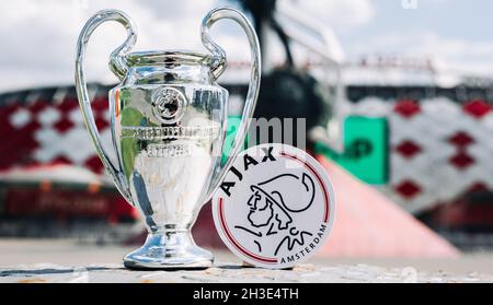 June 14, 2021 Amsterdam, Netherlands. The emblem of the AFC Ajax football club and the UEFA Champions League Cup against the backdrop of a modern stad Stock Photo