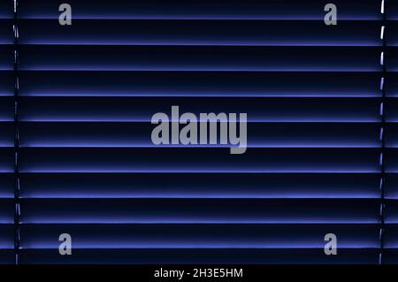 Window blinds in colors from blue to purple and black with gaps between the stripes close-up Stock Photo