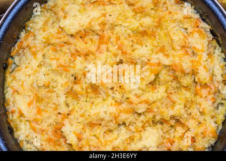 Top view of traditional Italian yellow risotto, closed view forming texture with rice grains, carrot, tomato, onion and green onion. Stock Photo