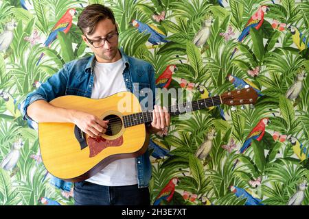 Young guy in sunglasses sitting on seat near blue sea and looking away in Jamaica Stock Photo