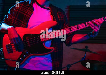 Crop anonymous male guitarist playing electric guitar in club with neon purple and blue lights Stock Photo