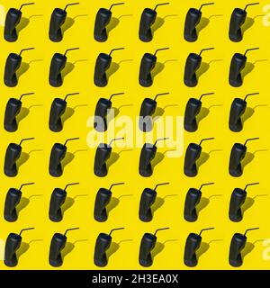Black crumpled empty used can of beverage with straw placed on yellow background in modern light creative studio with shadow Stock Photo