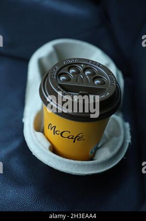 A McDonald's menu in a car. Here's a coffee mug at the seat with the text McCafé. McCafé is a coffee-house-style food and beverage chain, owned by McDonald's. Stock Photo