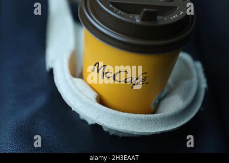 A McDonald's menu in a car. Here's a coffee mug at the seat with the text McCafé. McCafé is a coffee-house-style food and beverage chain, owned by McDonald's. Stock Photo
