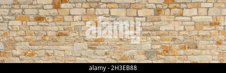 Panoramic stone wall made of old natural stones in beige, ocher and brown Stock Photo