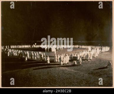 Vintage photo dated showing members of the Ku Klux Klan attending a night time gathering dressed in klan robes and hoods with a burning cross in Jackson County Mississippi Stock Photo