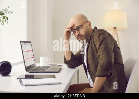 Busy man overwhelmed with work using calendar on laptop and planning his schedule Stock Photo