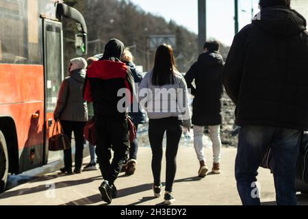 People get on the bus. A lot of people are queuing up for the bus. Public transport in the city. People are waiting to board the transport. Stock Photo