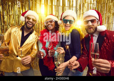 Happy people in party santa claus hat holding sparklers and champagne glasses Stock Photo