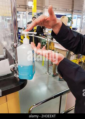 Kiev Ukraine 05/05/2020 male hands click on a dispenser bottle with a sanitizer near the cash desk of a supermarket during the coronavirus epidemic. P Stock Photo