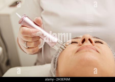 Lovely woman receiving radiofrequency treatment at wellness center Stock Photo