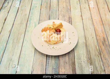 Russian salad with boiled egg and potatoes, mayonnaise, grated carrot, cooked prawns, stale bread and parsley served as Spanish tapas Stock Photo