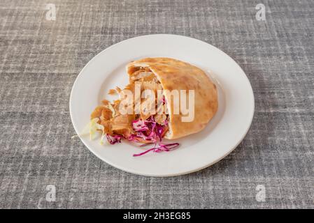 Sliced grilled lamb doner kebab sandwich with onion, purple cabbage, lettuce and tomato with yogurt sauce on gray table Stock Photo