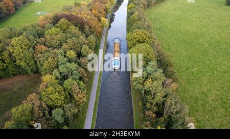 Aerial 4K Bird view shot with a drone of waterway with a barge or freight cargo ship sailing across the natural green orest and farmfield area . High quality 4k footage Stock Photo