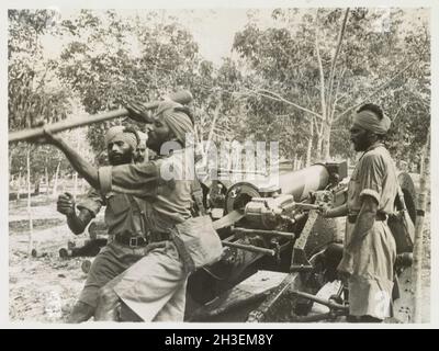 A vintage photo circa 1941 of Sikh soldiers of the Indian Army manning an artillery gun in the jungle prior to the Japanese invasion of Malaya and the fall of Singapore Stock Photo