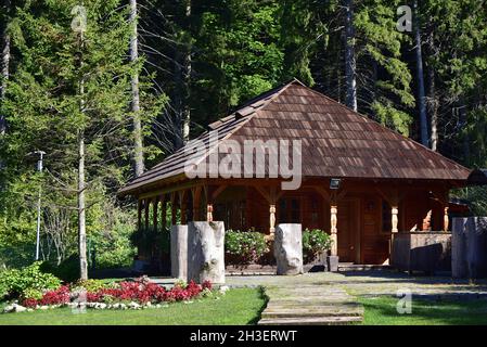 Facade of a wooden countryside house surrounded by beautiful tall green trees on a sunny day Stock Photo