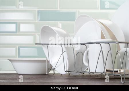 Dish rack with clean dry dishes on kitchen counter Stock Photo