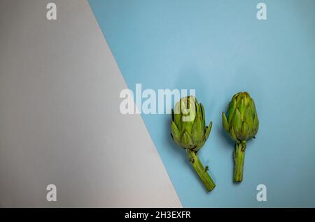 Two artichokes on grey and blue background Stock Photo
