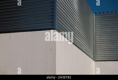 Closeup of white wall and metal wall against blue sky Stock Photo