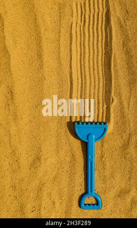 children's plastic rake lying on the yellow sand. High quality photo Stock Photo