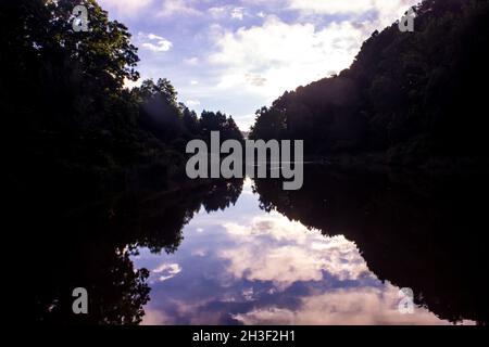 Pink clouds at sunset, reflecting in a small lake, surrounded by trees in Magoebaskloof, just outside Haenertsburg, South Africa. Stock Photo