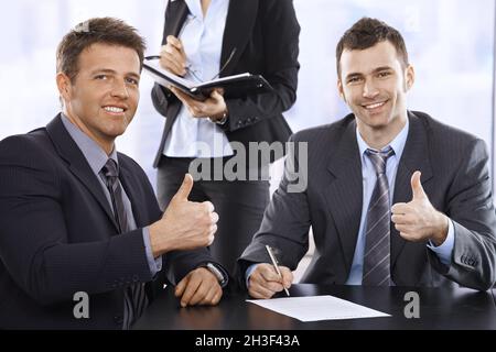 Businessmen giving the thumbs up, smiling Stock Photo