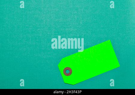 Green blank label tag on a teal cardstock background with copy space, conceptual image. Stock Photo