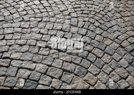 Many small stone blocks stacked side by side make up the surface of a paved road or sidewalk. Stock Photo