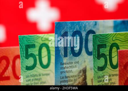 The symbols of the Swiss flag is seen behind the Swiss banknotes of various denominations. These new banknotes are the eighth series of banknotes whic Stock Photo