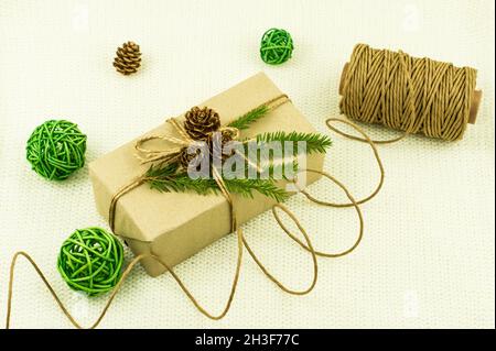 New Year's holiday box with a gift, decorated with your own hands and wrapped in kraft paper. green branches of spruce, cones, decorative balls Stock Photo