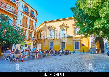 GRANADA, SPAIN - SEPT 27, 2019: University Square with outdoor cafes and historic building of Faculty of Law of Granada University, decorated with Sol Stock Photo