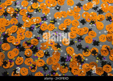 Halloween background: confetti in the shape of orange pumpkins, black spiders and stars. Copy space. Stock Photo