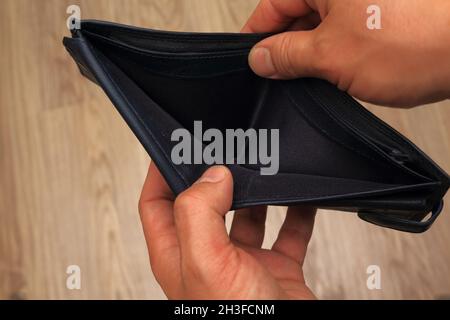 Poor man hand open empty wallet looking for money, broke, bankrupt or crisis concept. Stock Photo