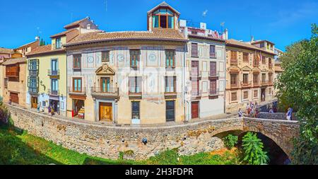 GRANADA, SPAIN - SEPTEMBER 27, 2019: Panorama of historic edifices, Espinosa Bridge, palace, decorated with frescoes and narrow Carrera del Darro stre