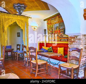 GRANADA, SPAIN - SEPTEMBER 27, 2019: Interior of traditional Arabic style teahouse with wooden furniture, carpets, Arabian lights and Islamic patterns