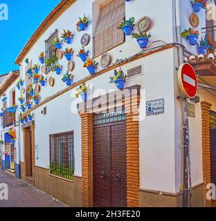 GRANADA, SPAIN - SEPTEMBER 27, 2019:  Exterior decoration of the white house in Panaderos street, the wall is covered with painted ceramic plates