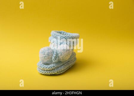 homemade knitted shoes for newborn boys on yellow background Stock Photo