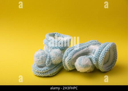 homemade knitted shoes for newborn boys on yellow background Stock Photo