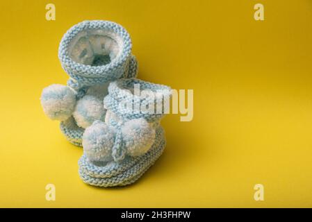 homemade knitted shoes for newborn boys on yellow background Stock Photo