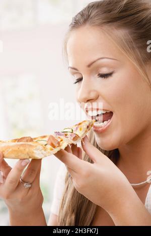 Young woman eating pizza slice Stock Photo